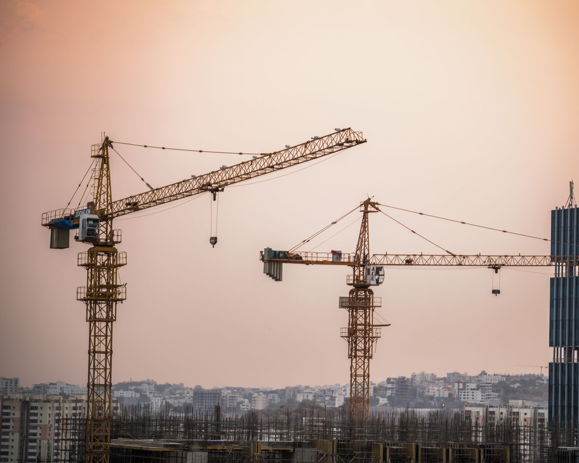 High-rise building under construction with tower cranes at dusk, built by Bhagya Lakshmi Construction